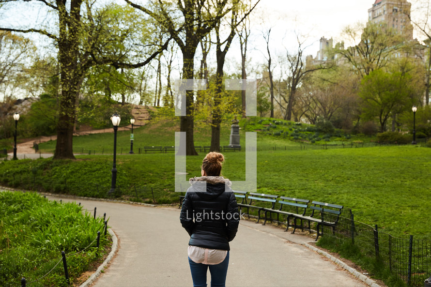 a woman walking on a path through a park 
