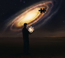 man holding the missing piece of the puzzle of the universe 