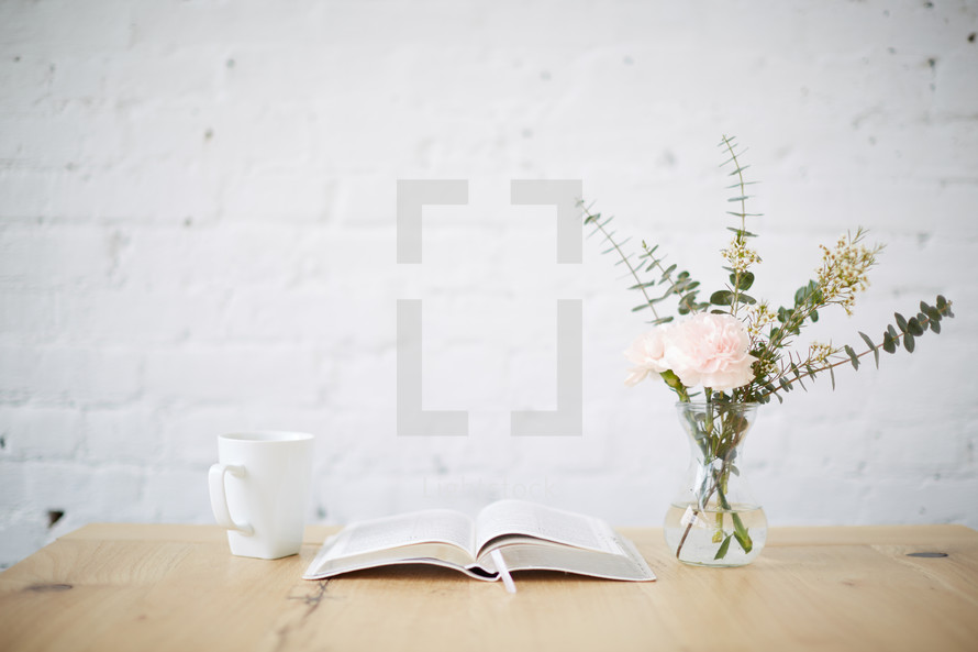 vase of flowers, open Bible, and coffee cup on a table 