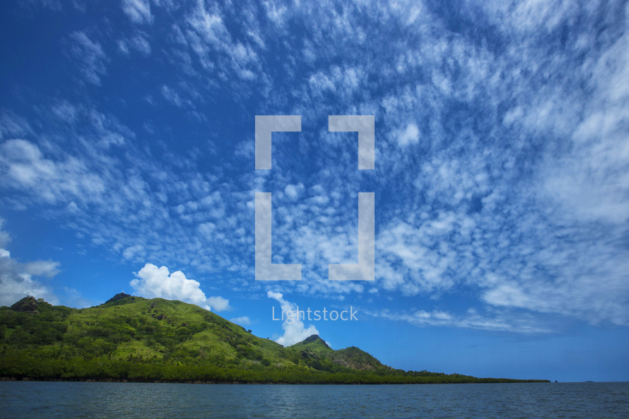clouds in a blue sky over the ocean  and an island