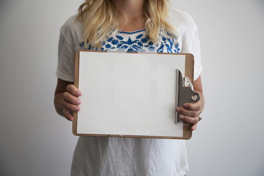 woman holding a blank piece of paper on a clipboard 