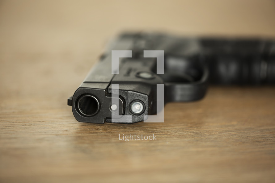 black pistol lying on a wooden table.
