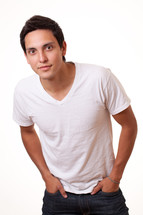 a young man in a white t-shirt with hands in his pockets 