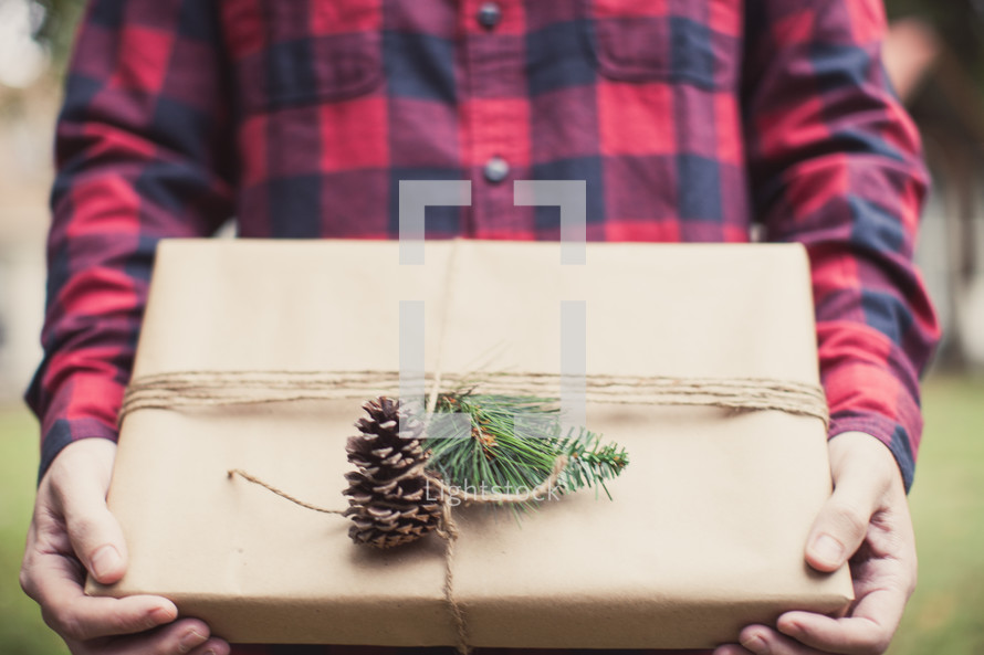 A man holding a gift wrapped in brown paper