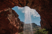 misting waterfall over a red rock cliff
