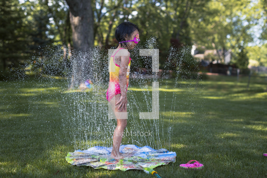 a child playing in a sprinkler 