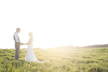 bride and groom holding hands outdoors under intense sunlight 