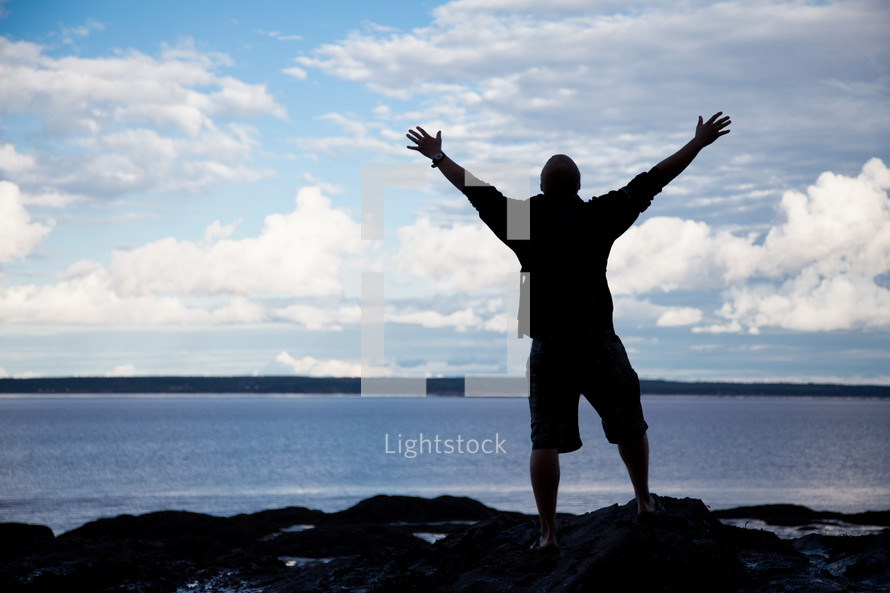 silhouette of a man with raised arms on a beach 
