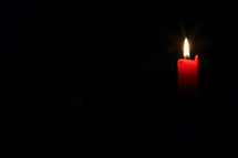 red candle in darkness 