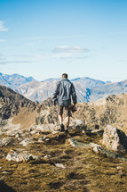 man hiking on a rugged mountain landscape carrying a Bible 