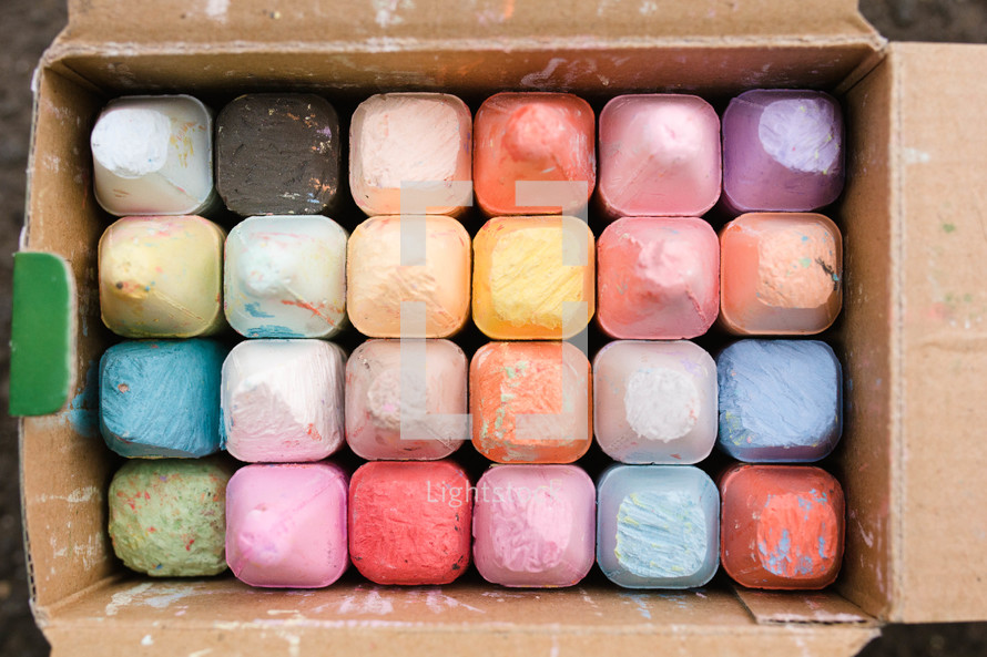 A cardboard box full of colorful sidewalk chalk.
