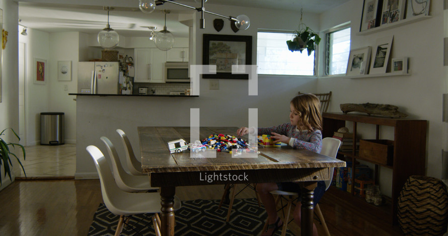 a child with building blocks at a dining room table 