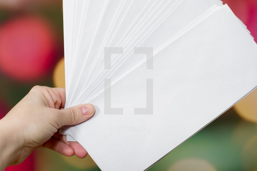 hand holding white envelopes 