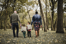 a family walking holdings hands in a park in fall 