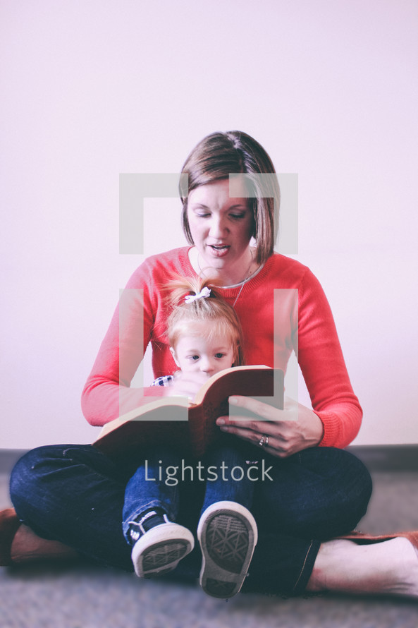 A woman reading to a child in her lap.
