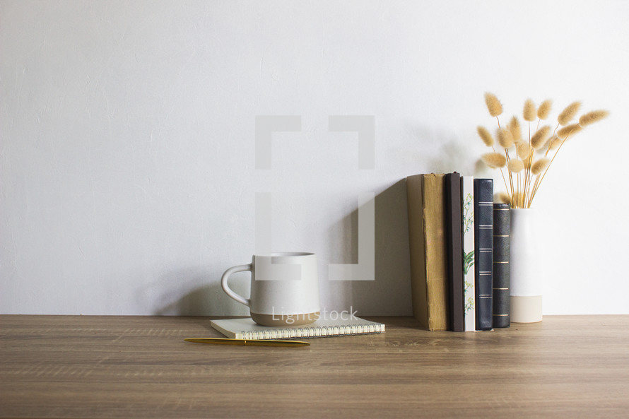 Study concept with coffee cups, books and flowers on brown wooden table. 