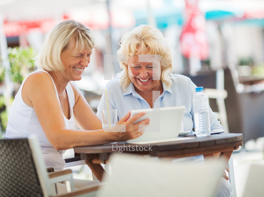 two women sitting looking at a tablet 