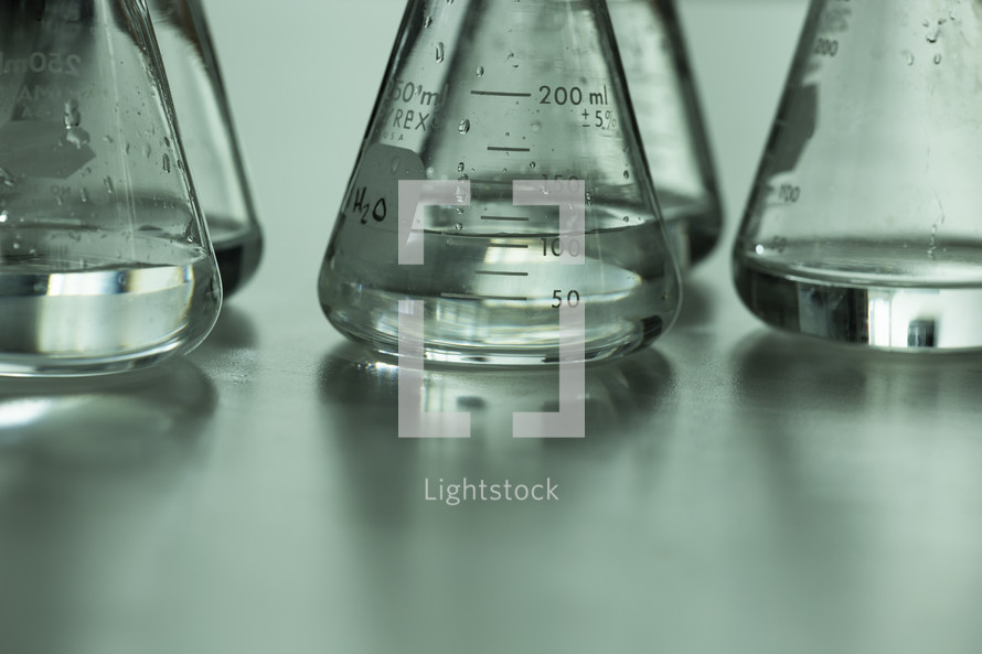 Clear liquid measured in glass scientific measuring flasks.