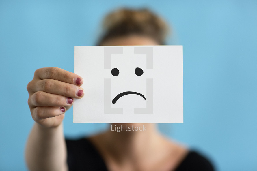 a woman holding a frown face 