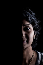 face of a woman standing in darkness 