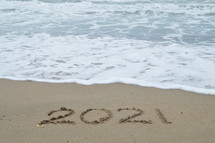 year 2021 written in sand 