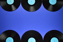 border of old black vinyl records with blank cyan labels on blue background