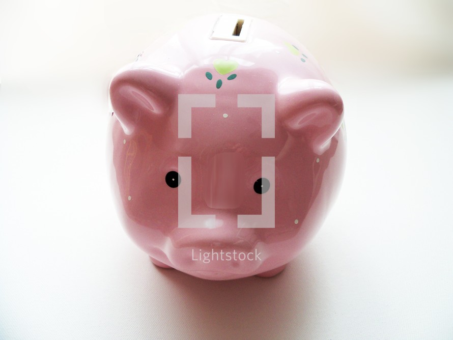 The front view of a piggy bank staring out against a white background encouraging people to save their money for the future for college, vacations, education, emergency funds or retirement.  Saving money is a discipline and when financial crisis occurs, we need to have savings to depend upon without having to borrow money from lenders and be able to meet our financial needs. Our heavenly father promises to provide for us in our time of need and even when we don't have need but we still need to be good stewards of our money and savings and invest properly to plan ahead for the future.  