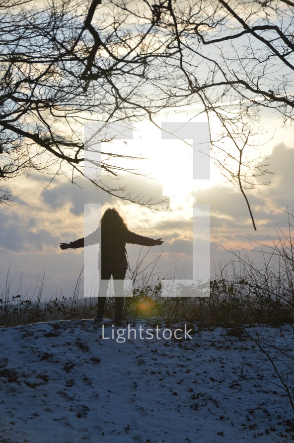 woman standing in the snow with outstretched arms 