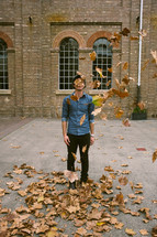 man tossing fall leaves into the air 