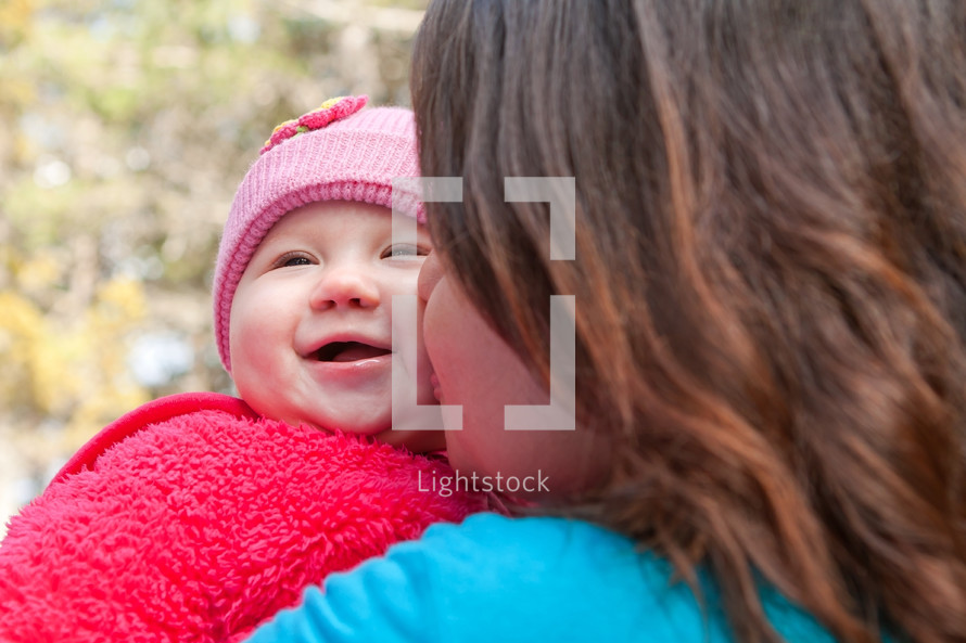 Woman kissing smiling baby on the cheek.