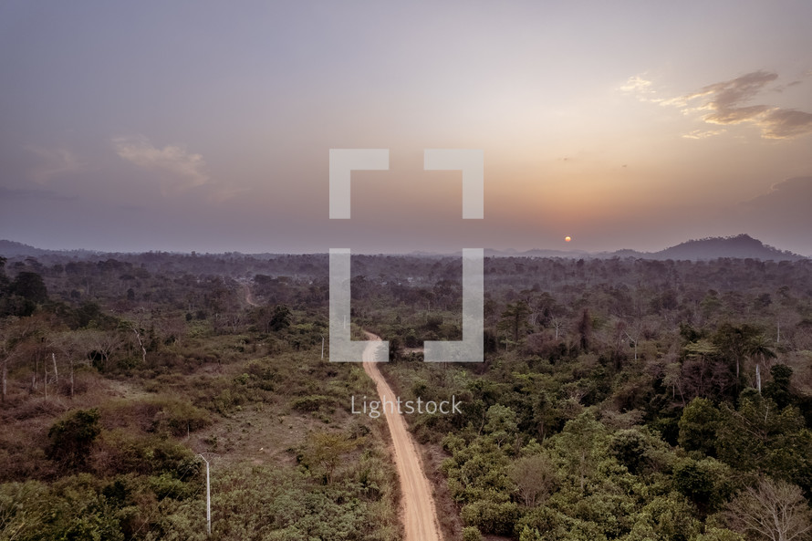 Sunset over the jungle in The Ivory Coast of West Africa with a dirt road 