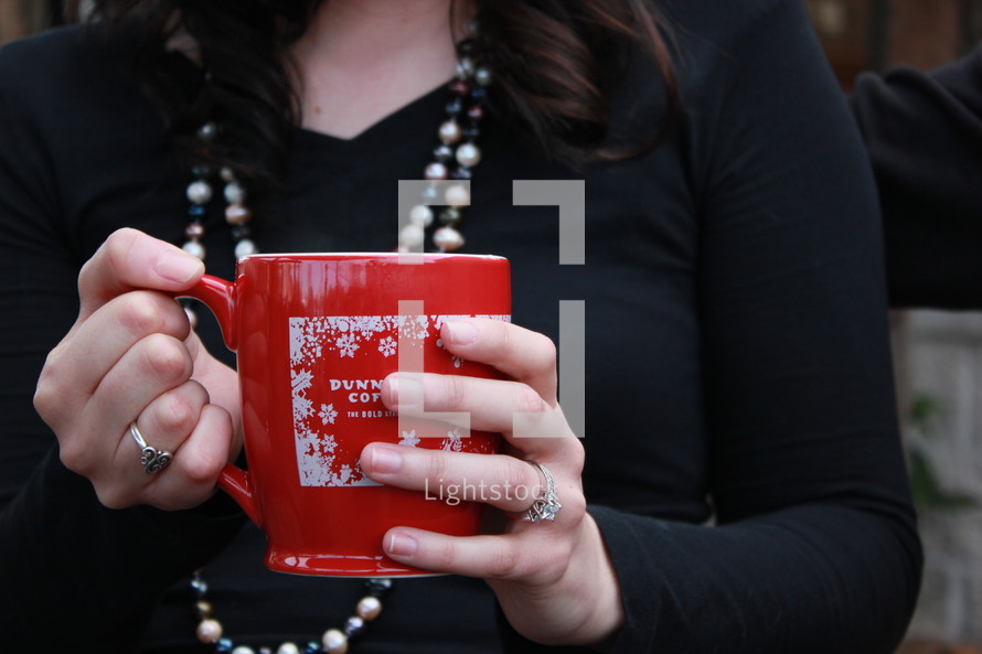 a woman holding a winter coffee mug 