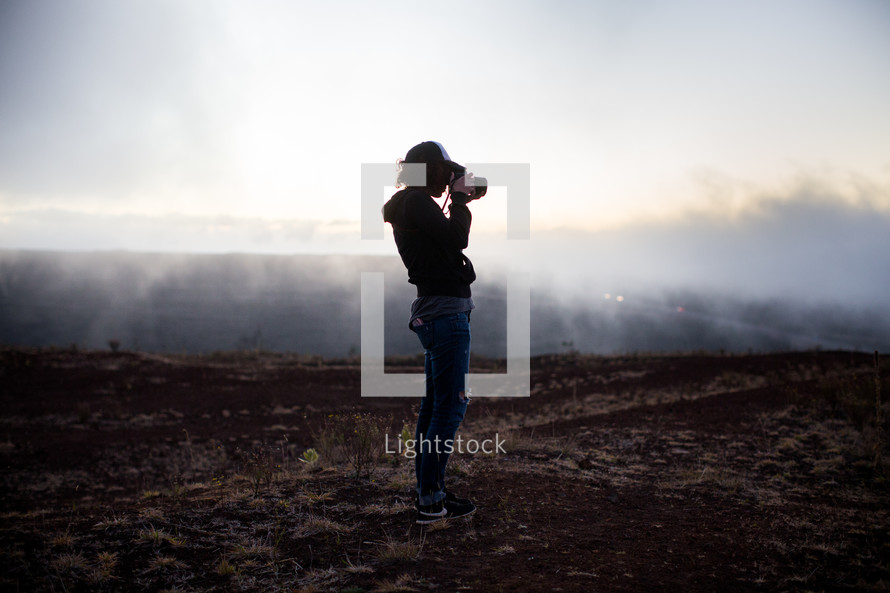 woman holding a camera in a foggy field 