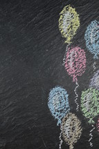 chalk on slate with flying balloons and copy space to the left side