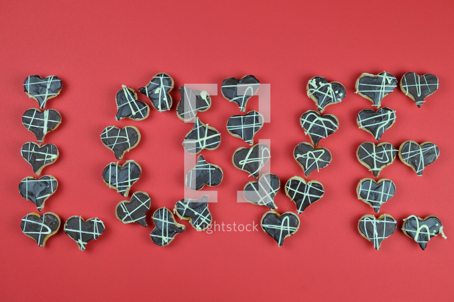 home made heart shaped cookies with chocolate on red background lettering the word love