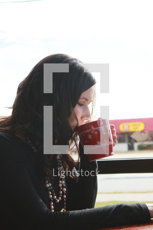 a woman sipping from a coffee mug 