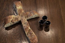 Bread in the shape of a cross with three goblets of wine