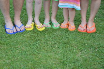 feet in colorful flip flops standing in the grass 
