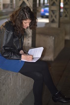 a woman sitting and writing in a journal 