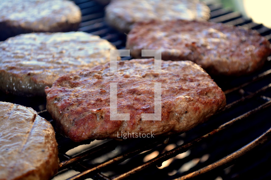 Hamburger patties cooking on a grill.