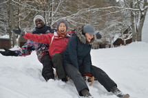 adults sledding in the snow 