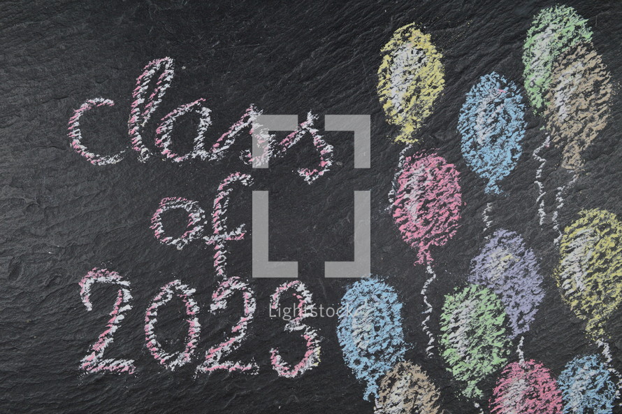 chalk on slate with balloons and the words: class of 2023