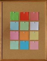 blank sticky notes pinned to a cork board 