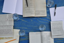 small group bible study with different bibles, notebooks, pens and glasses on a blue wooden table