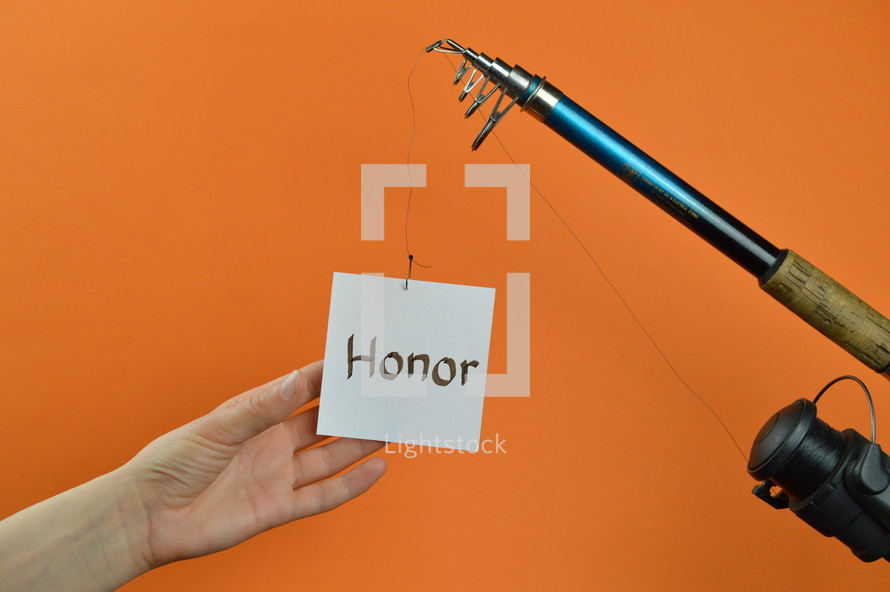 a hand reaching for a piece of paper with the word HONOR on it hanging from a fishing line 