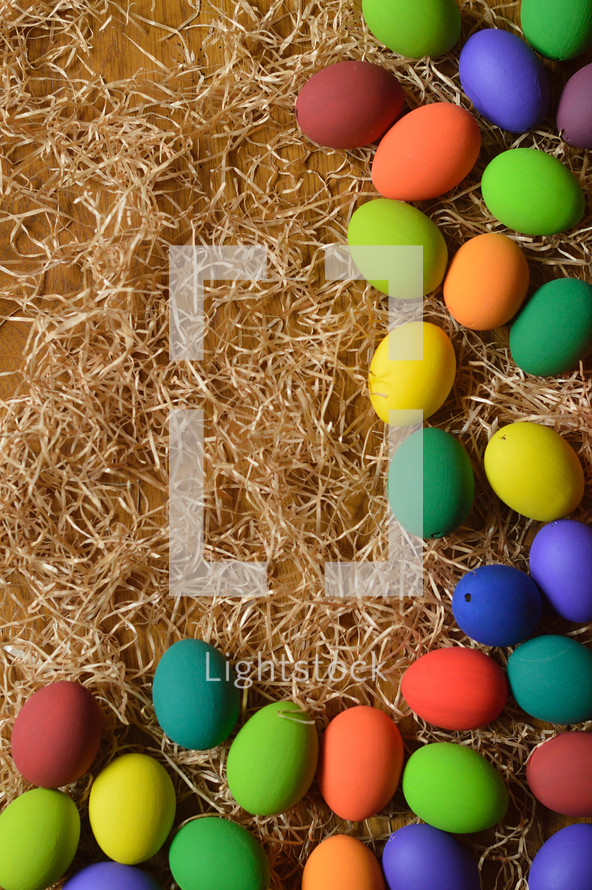 border of colorful Easter eggs on straw 