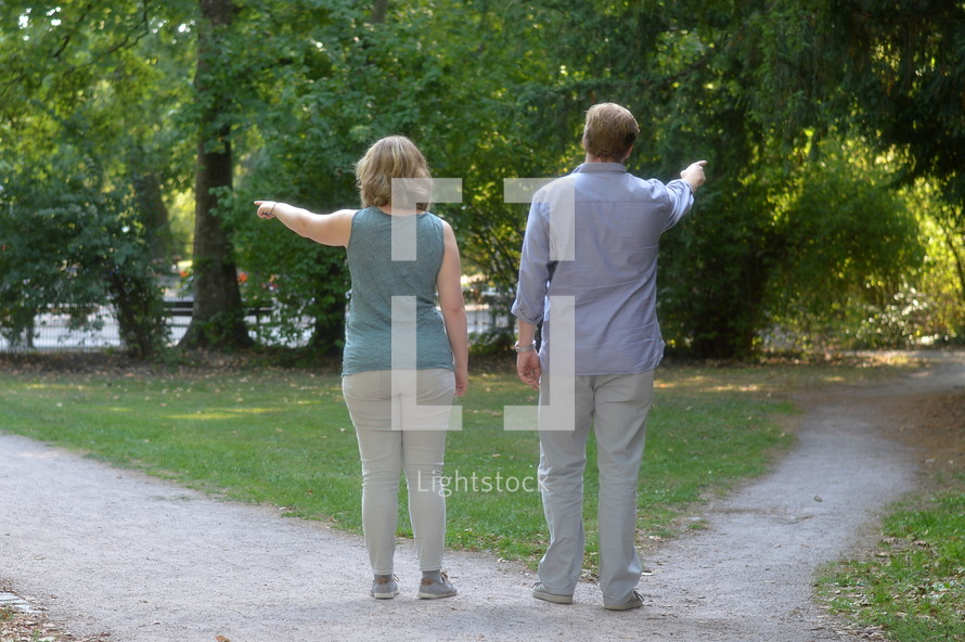 man and woman pointing down different paths