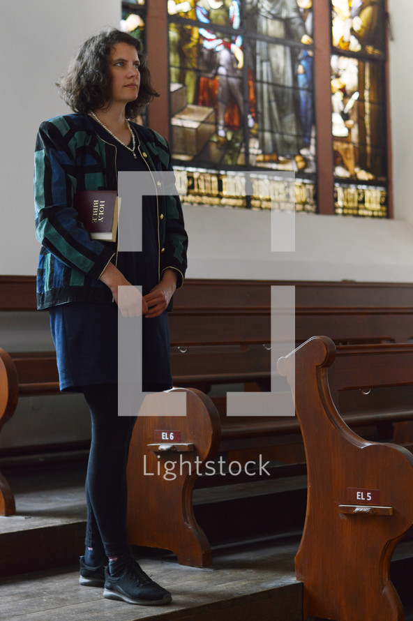 a woman walking into an empty church with her Bible 