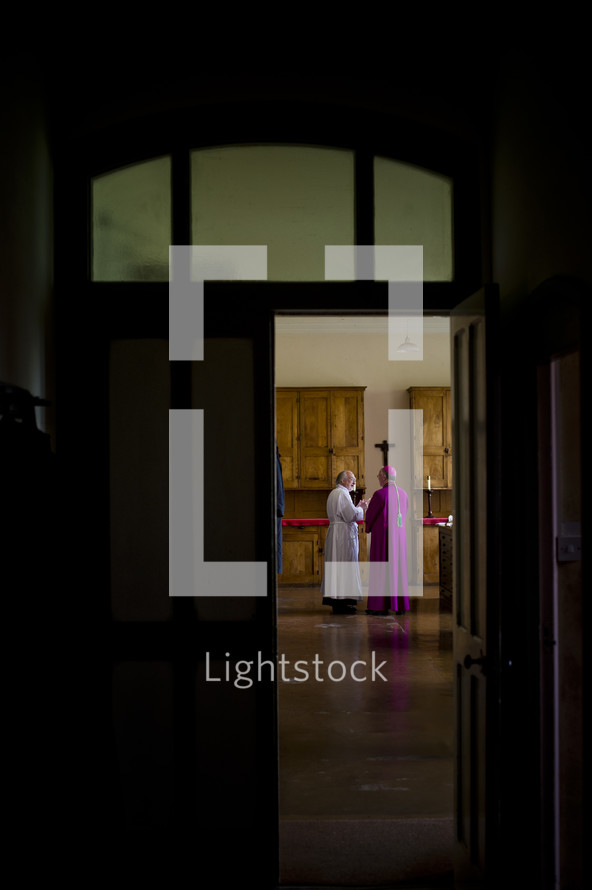 priest and bishop through a door 