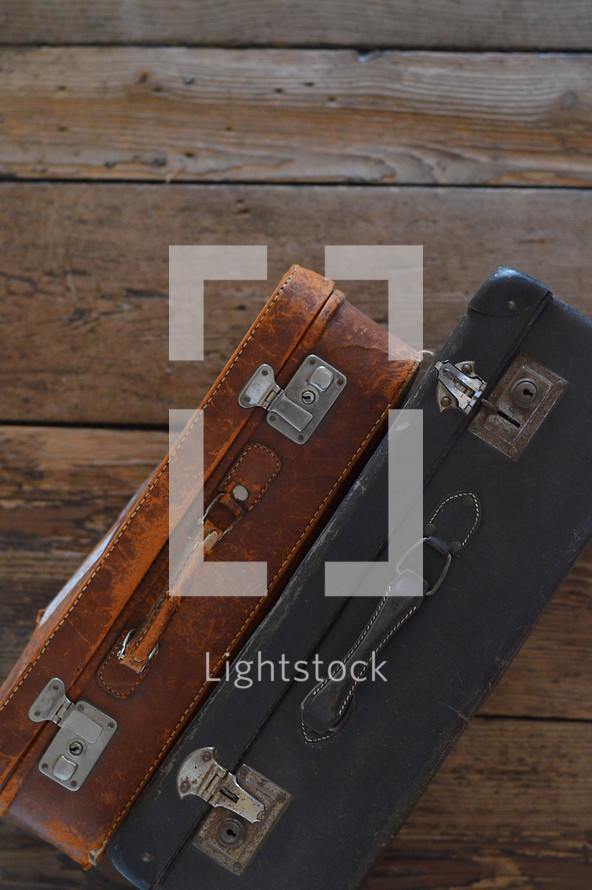 two old weathered suitcases on a rustic wooden floor
